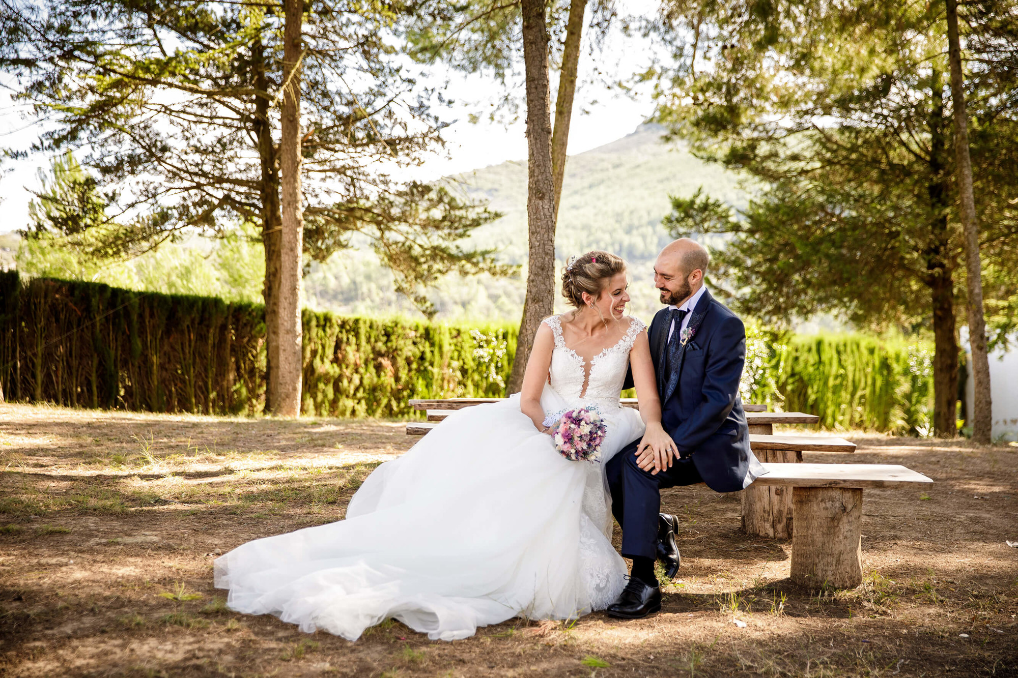 Los novios en el bosque sentados en un banco en Masia Torreblanca.