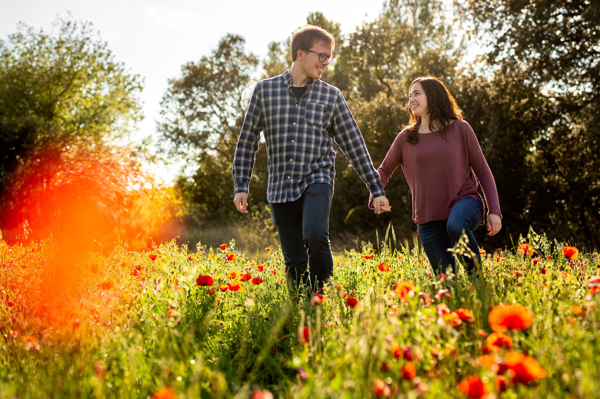 Sessió preboda la parella passeja en un camp de roselles o amapoles al Penedès.