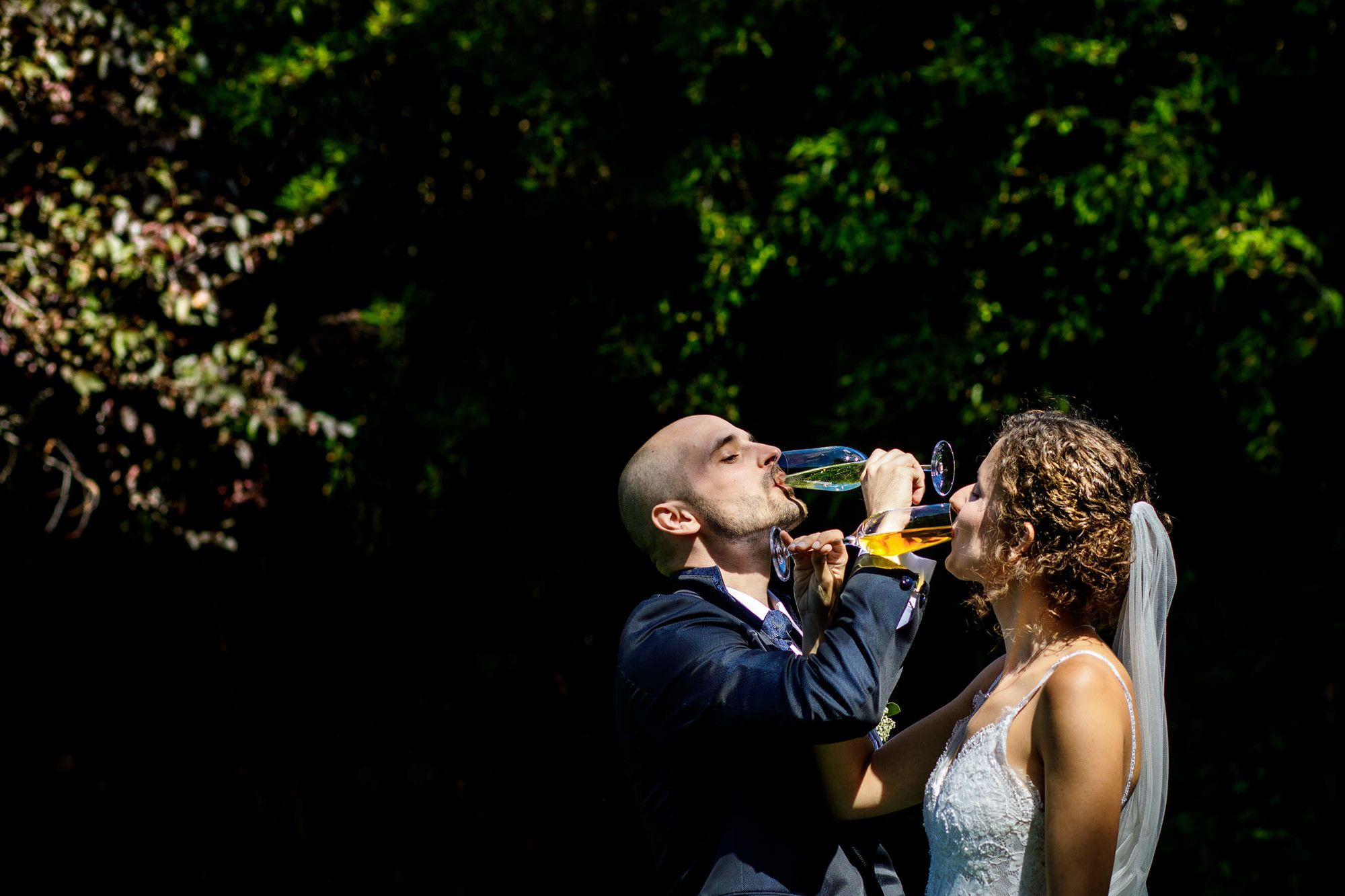 Els nuvis beuen cava a l'aperitiu al jardí a la boda a Masia Papiol.